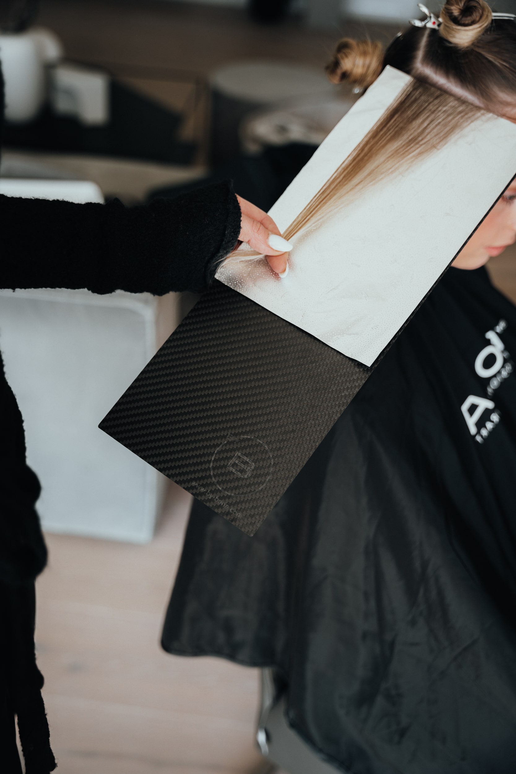 Haare einer Frau werden auf dem Hairboard aufgelegt um sie mit Farbe zu bestreichen
